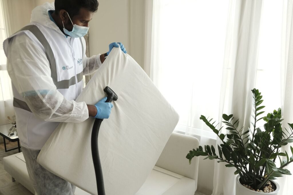 Technician vacuuming a mattress with a handheld tool