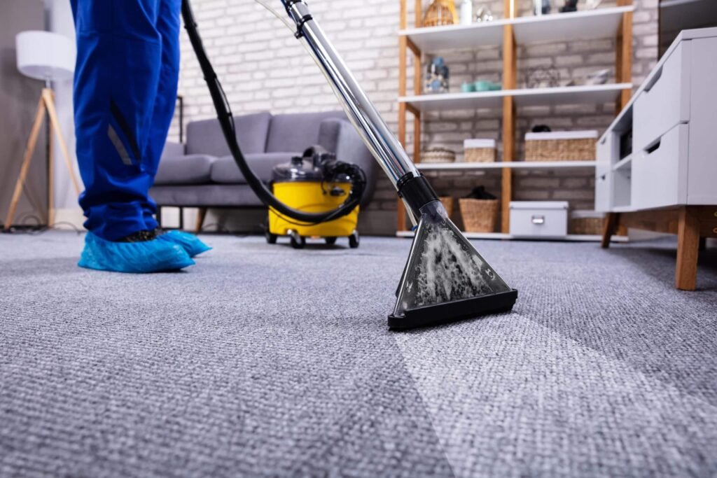 Cleaner using a carpet cleaning machine on grey carpet in a living room