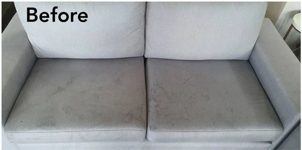 Grey fabric loveseat with marks and stains on the seat cushions, before cleaning